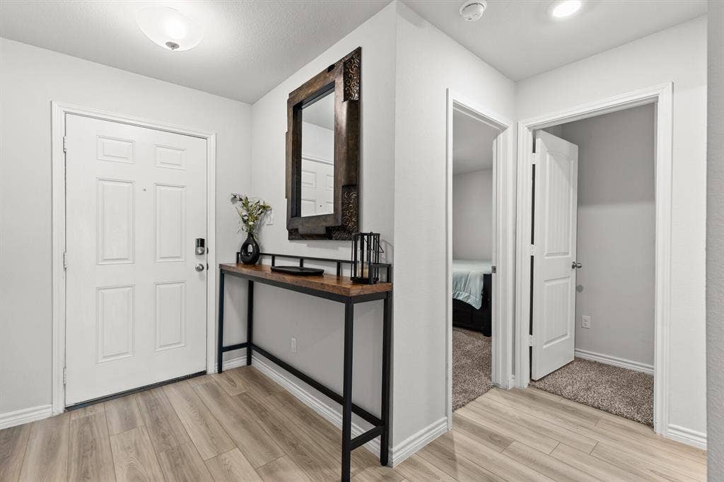Entryway featuring wood-finish flooring, a contemporary console table, and a decorative mirror