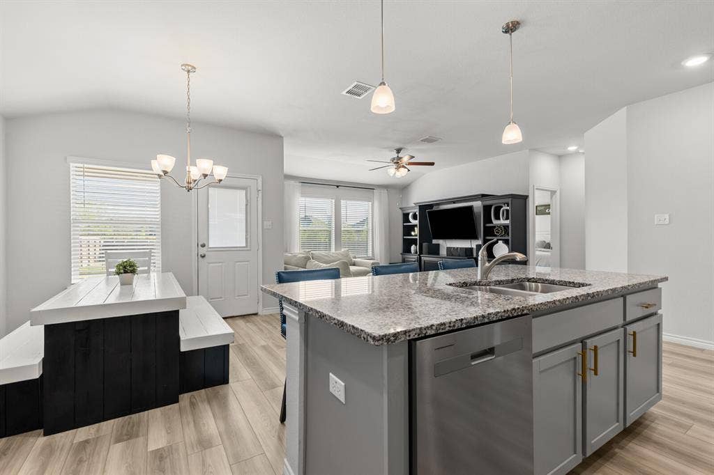 Kitchen island with a stainless steel sink and faucet, integrated dishwasher, and granite countertop