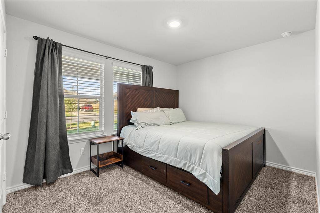 Carpeted room featuring multiple windows with blinds, recessed lighting, and white walls (actual room 1)