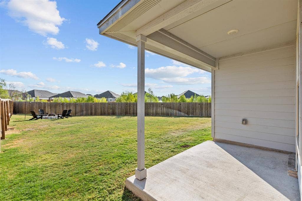 Expansive backyard with a wooden fence, concrete patio, and mature landscaping