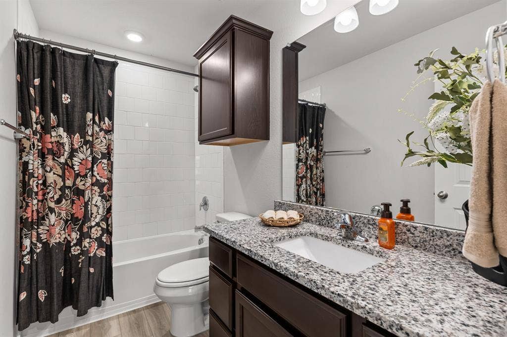 Bathroom featuring a vanity with a granite countertop, undermount sink, and wood-finish cabinetry