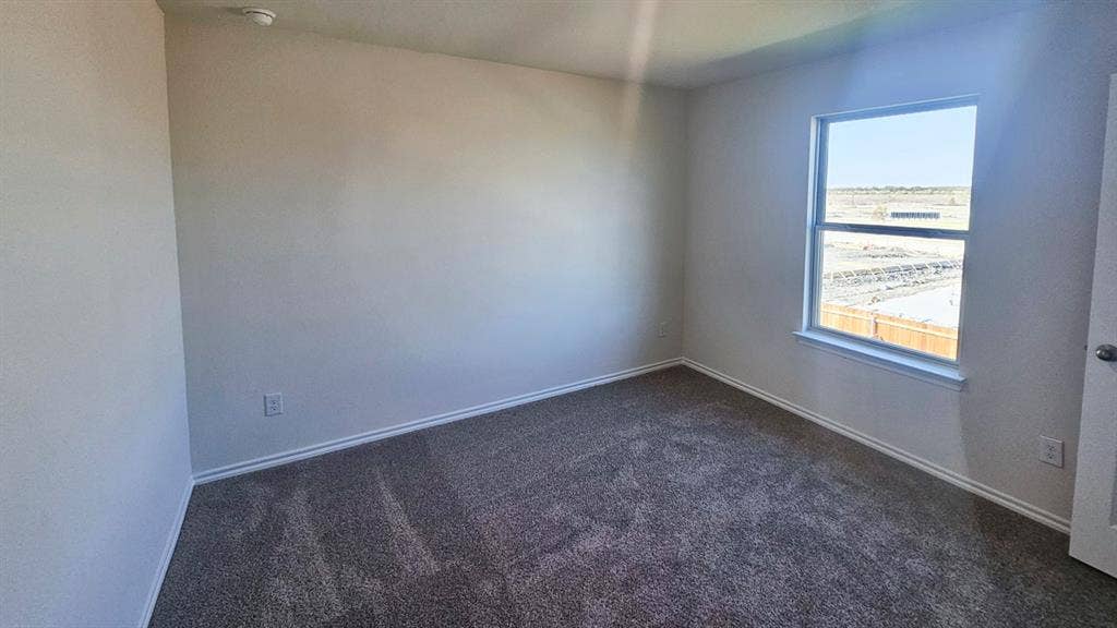 Spacious room featuring neutral carpeting, light-toned wall paint, and white baseboards