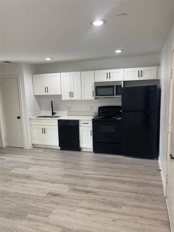 321 E 8th Street, #218, Dallas, TX 75203 Kitchen featuring white shaker cabinetry, white countertops, stainless steel sink with matte black faucet, and a suite of black appliances including a refrigerator, dishwasher, and range