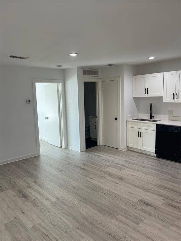 321 E 8th Street, #218, Dallas, TX 75203 Recessed ceiling lighting, wood-finish flooring, white cabinetry with black hardware, black dishwasher, and a black faucet