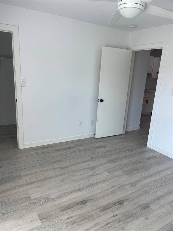 321 E 8th Street, #218, Dallas, TX 75203 Wood-finish flooring, white walls, white ceiling fan, and white doors