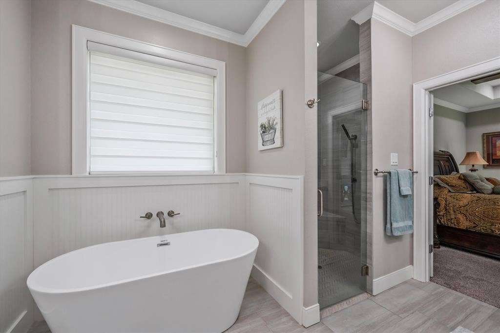 14486 Meadow Glen, Lindale, TX 75771 Freestanding soaking tub with a wall-mounted faucet, glass-enclosed shower, and wainscoting paneling
