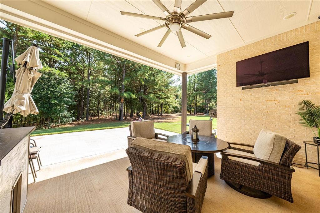 14486 Meadow Glen, Lindale, TX 75771 Covered patio featuring a ceiling fan, a mounted television, a textured accent wall, and a concrete floor