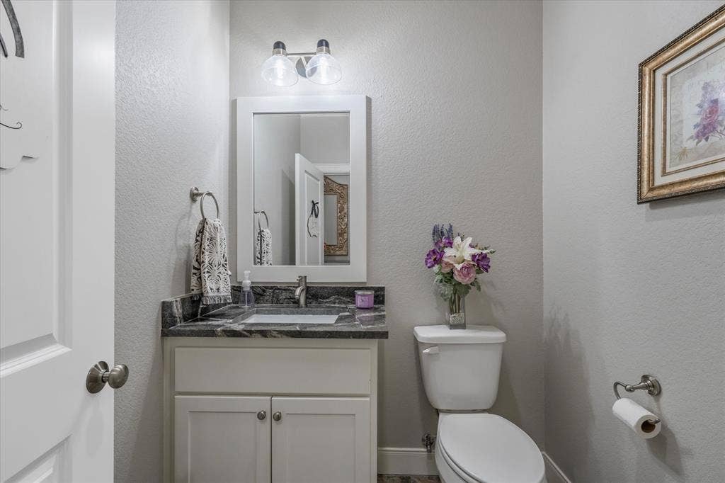14486 Meadow Glen, Lindale, TX 75771 White vanity with undermount sink, dark stone countertop, and two-light vanity fixture