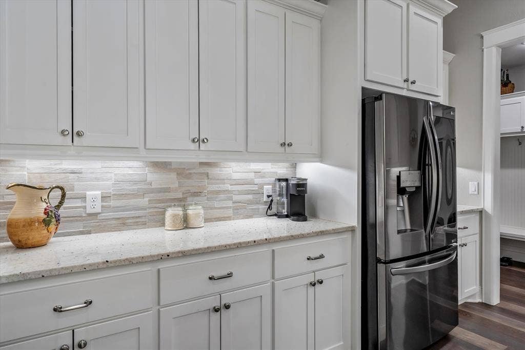 14486 Meadow Glen, Lindale, TX 75771 White shaker-style cabinetry, light-toned stone-finish countertops, stainless steel French door refrigerator, and stacked linear tile backsplash