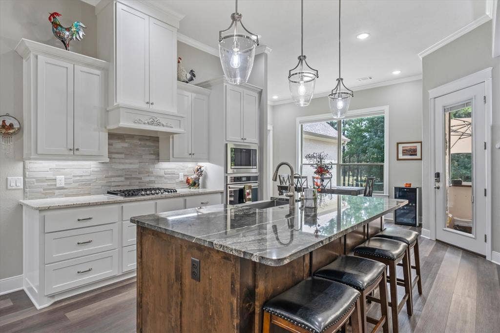 14486 Meadow Glen, Lindale, TX 75771 Kitchen featuring white shaker-style cabinetry, granite countertops, a gas range, stainless steel built-in appliances, and a central island with seating