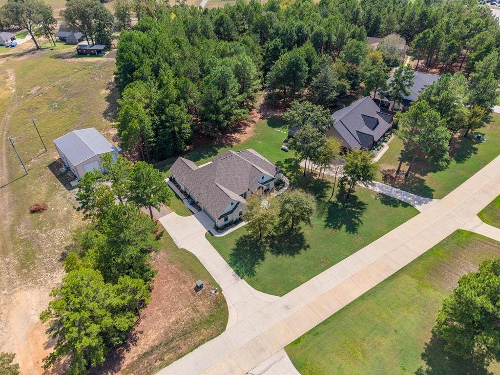 14486 Meadow Glen, Lindale, TX 75771 Expansive property featuring a single-story residence, separate metal-roofed outbuilding, concrete driveway, and mature trees