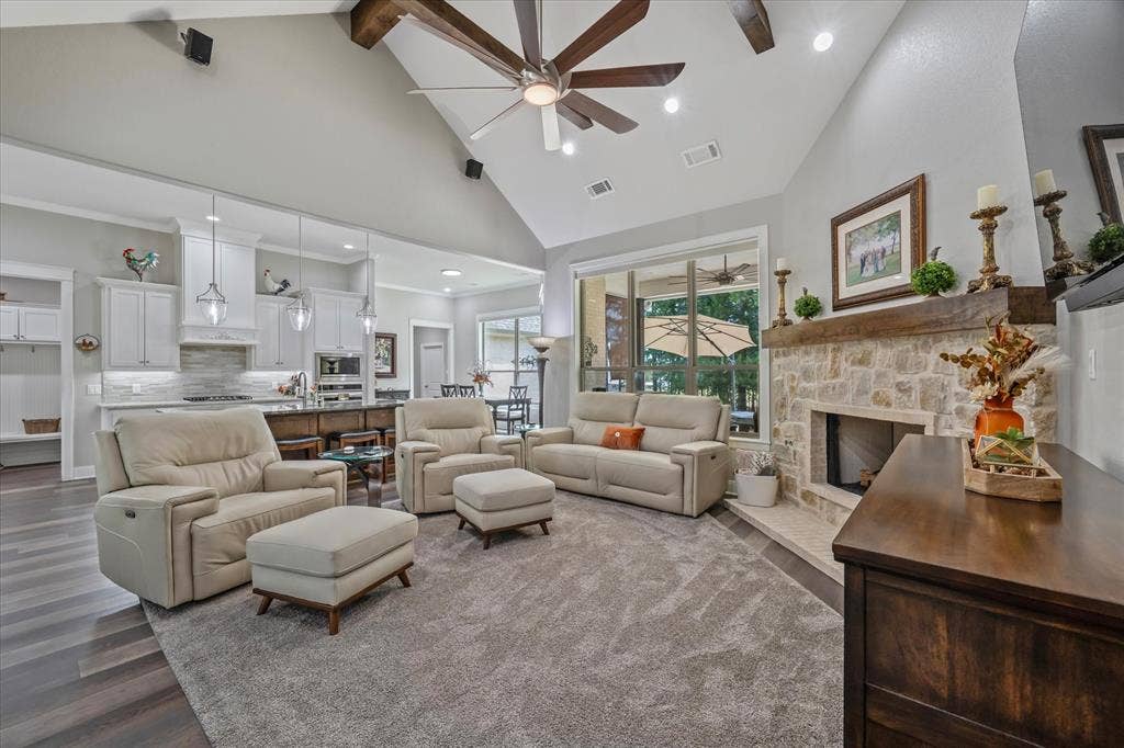 14486 Meadow Glen, Lindale, TX 75771 Vaulted ceiling with exposed wood beams, stone fireplace with a wood mantle, wood-finish flooring, white cabinetry, and pendant lighting