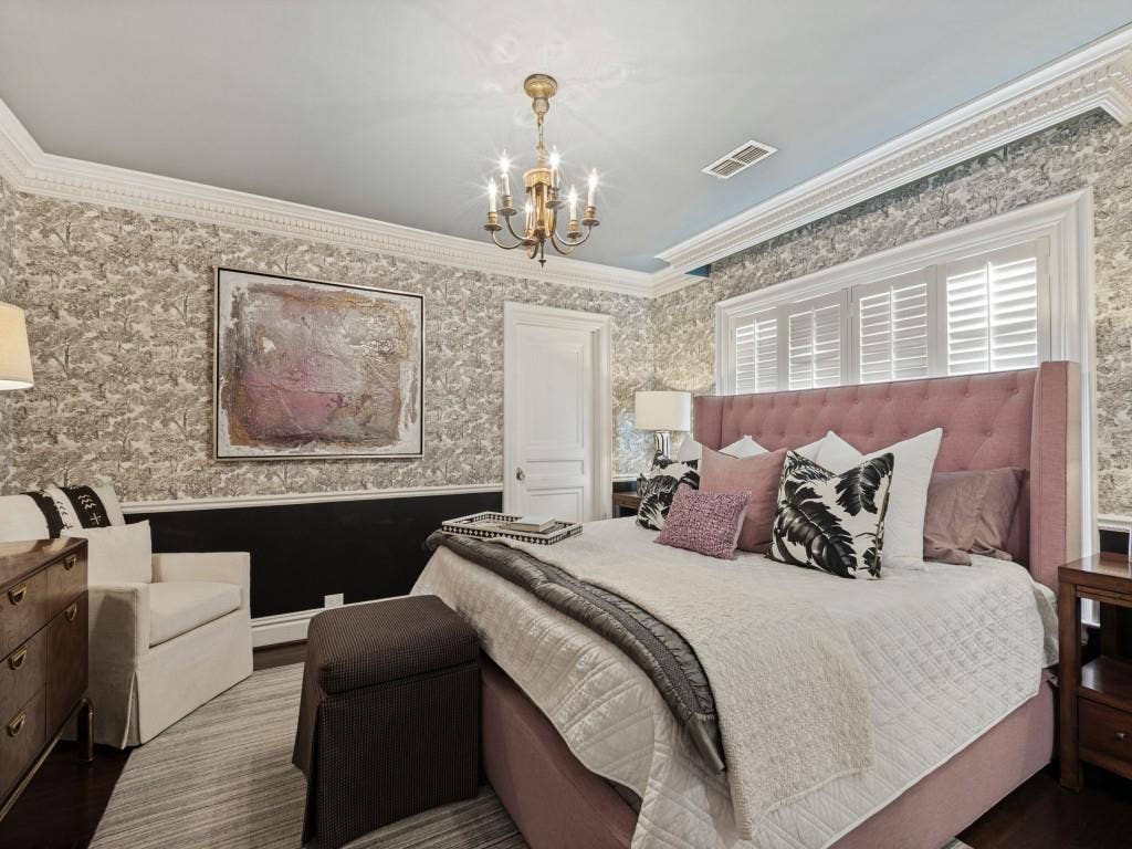 6858 Tokalon Drive, Dallas, TX 75214 Bedroom featuring detailed crown molding, floor-to-ceiling patterned wall coverings, shutter-style window treatments, and a hanging metal chandelier