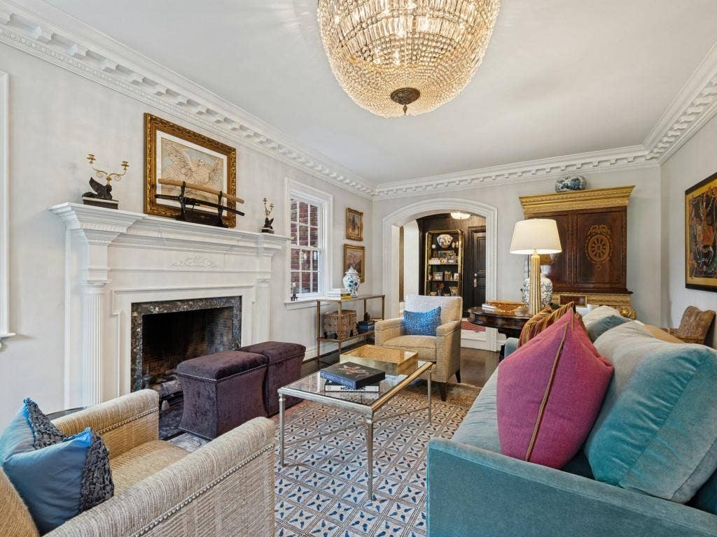 6858 Tokalon Drive, Dallas, TX 75214 Living room featuring a detailed fireplace mantel, crown molding, arched entry, and a crystal chandelier