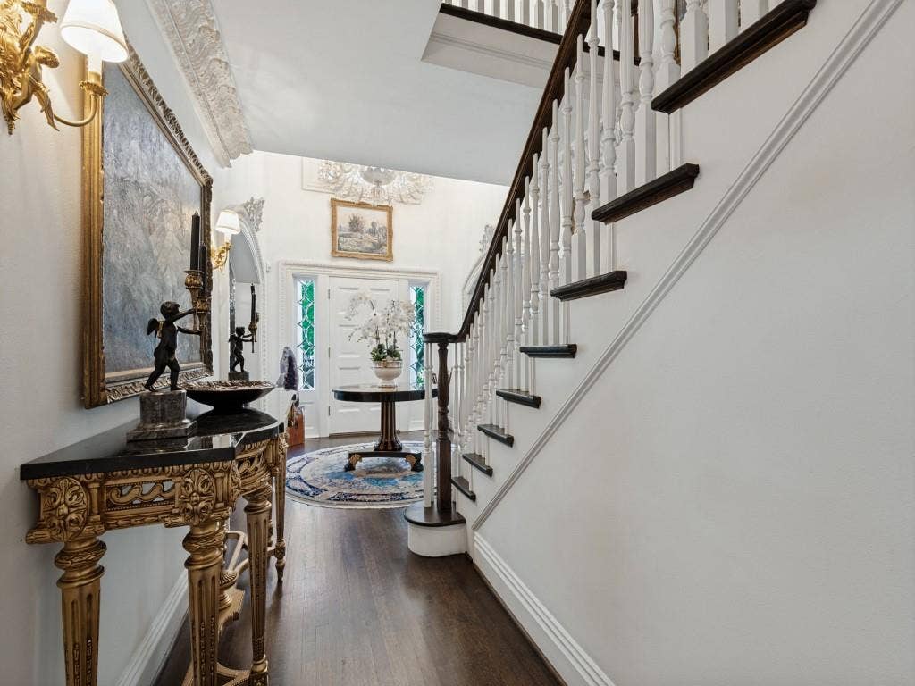 6858 Tokalon Drive, Dallas, TX 75214 Foyer featuring wood-finish flooring, a staircase with white balusters and dark-toned treads, intricate crown molding, and an arched entry door with sidelights