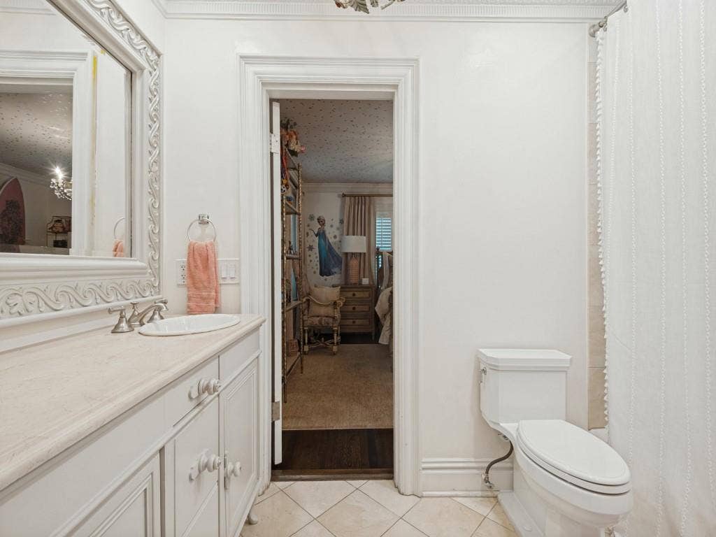 6858 Tokalon Drive, Dallas, TX 75214 Vanity with a neutral-toned countertop and an integrated oval sink, ornate framed wall mirror, and tile flooring