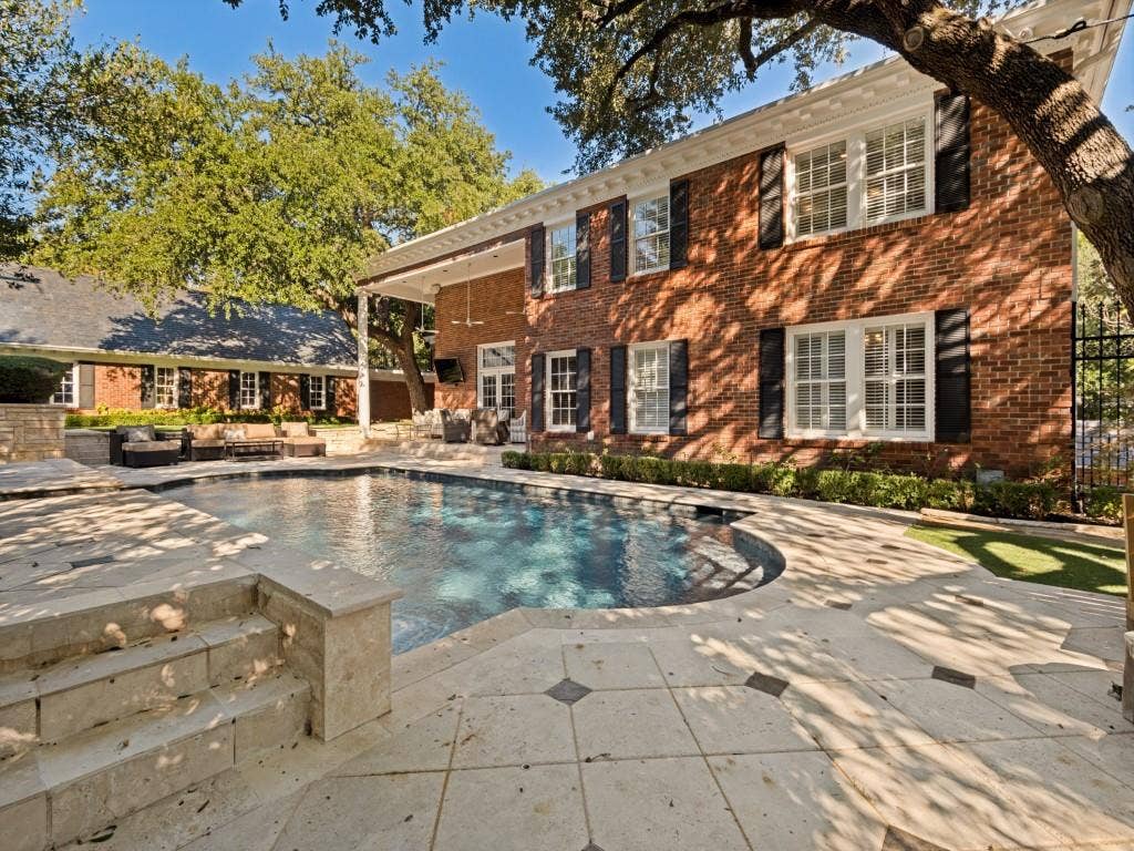 6858 Tokalon Drive, Dallas, TX 75214 Brick exterior featuring a covered patio, stone pool decking, and an in-ground swimming pool