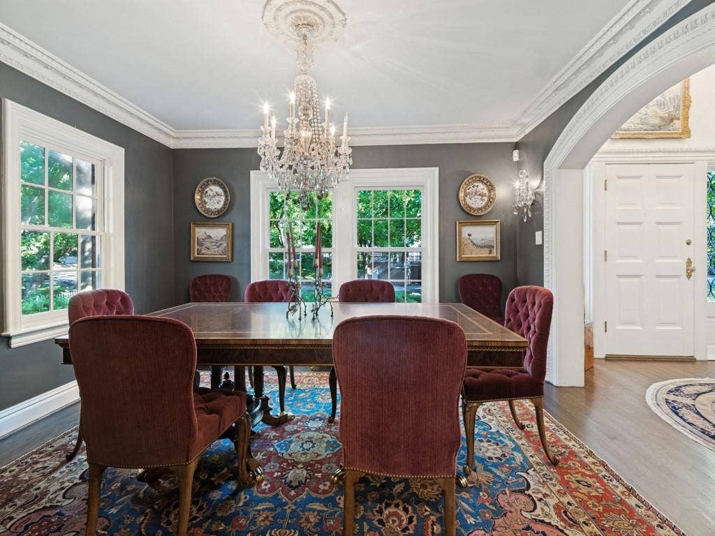 6858 Tokalon Drive, Dallas, TX 75214 Formal dining room featuring intricate crown molding, a decorative ceiling medallion, a multi-tiered crystal chandelier, wood-finish flooring, and a wide arched entryway