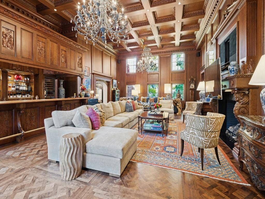 6858 Tokalon Drive, Dallas, TX 75214 Coffered wood ceiling, intricate wood-paneled walls, built-in wet bar, herringbone-patterned wood flooring, and an ornate fireplace surround