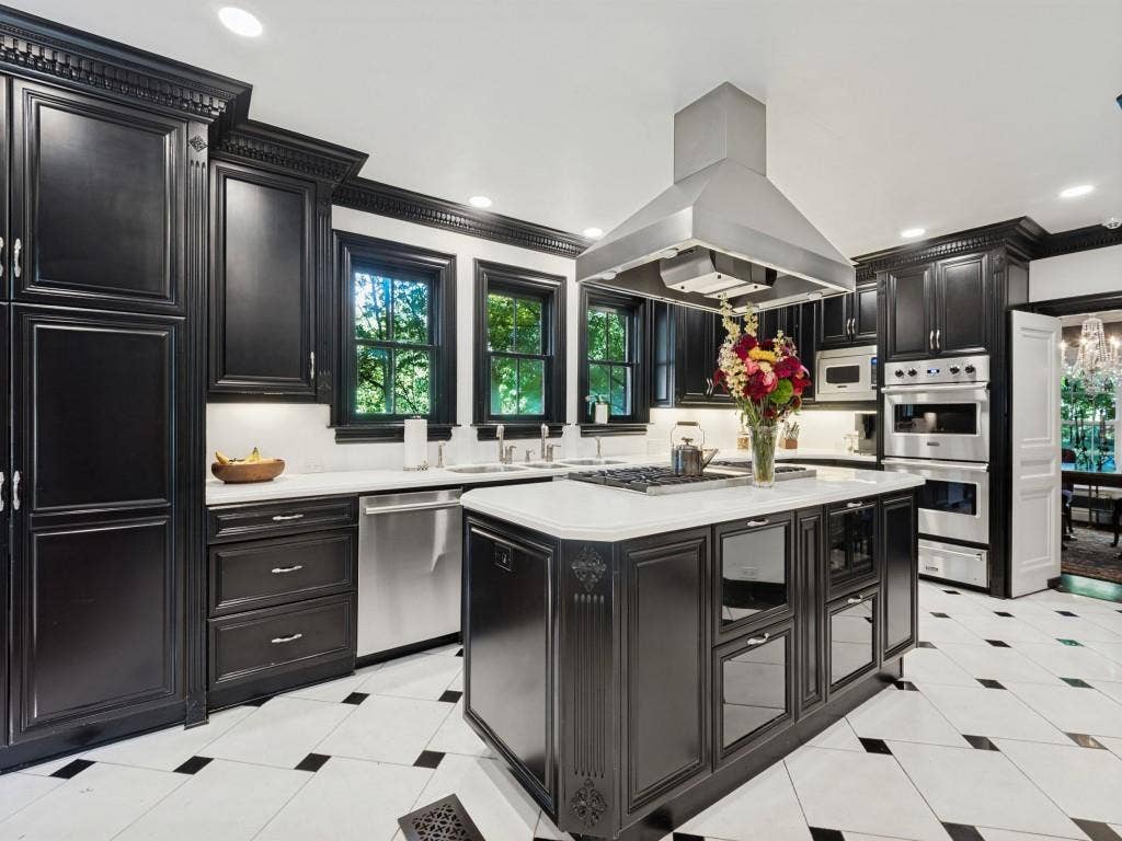 6858 Tokalon Drive, Dallas, TX 75214 Custom dark cabinetry with ornate crown molding, expansive stone countertops, stainless steel appliances, a central island with a built-in gas cooktop, and polished tile flooring with decorative inlay