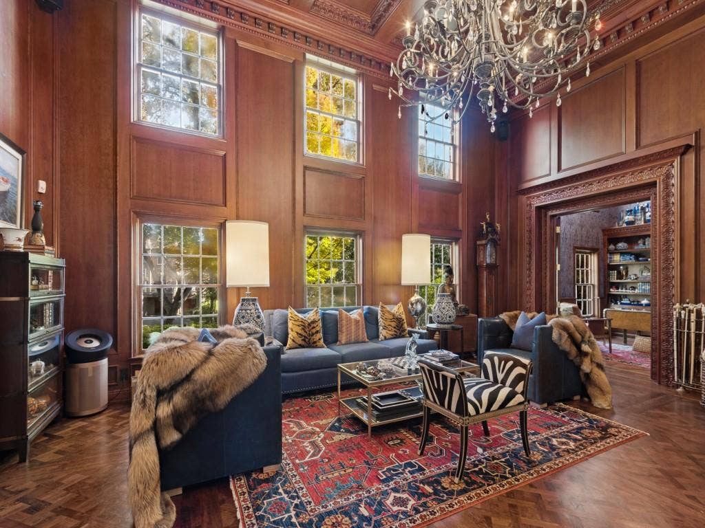6858 Tokalon Drive, Dallas, TX 75214 Two-story room featuring floor-to-ceiling wood paneling, herringbone-patterned wood flooring, an ornate multi-tiered crystal chandelier, and deep crown molding