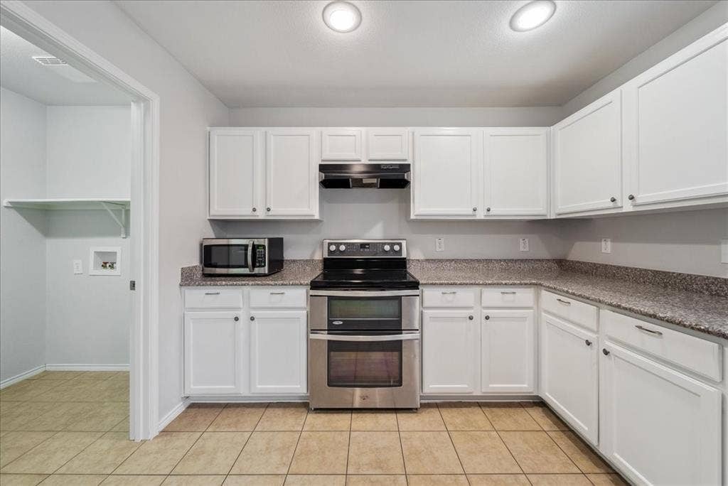 Kitchen featuring white cabinetry, stainless steel double oven range, and light-toned tile flooring