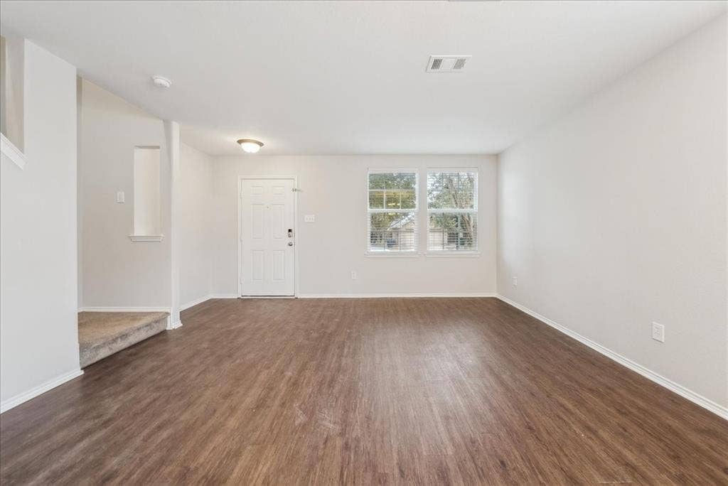 Expansive living area featuring wood-finish flooring, neutral wall tones, and recessed lighting