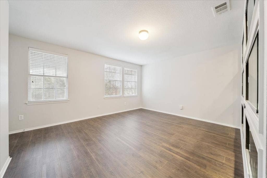 Wood-finish flooring, multiple windows with blinds, recessed ceiling light, and built-in shelving