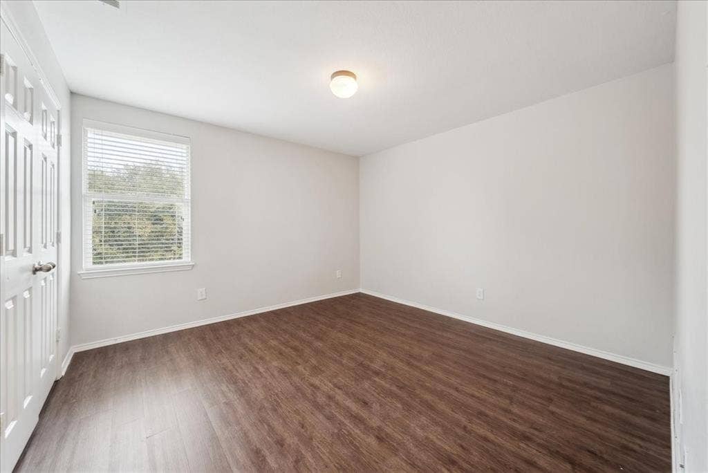 Wood-finish flooring, white painted walls, and a window with horizontal blinds