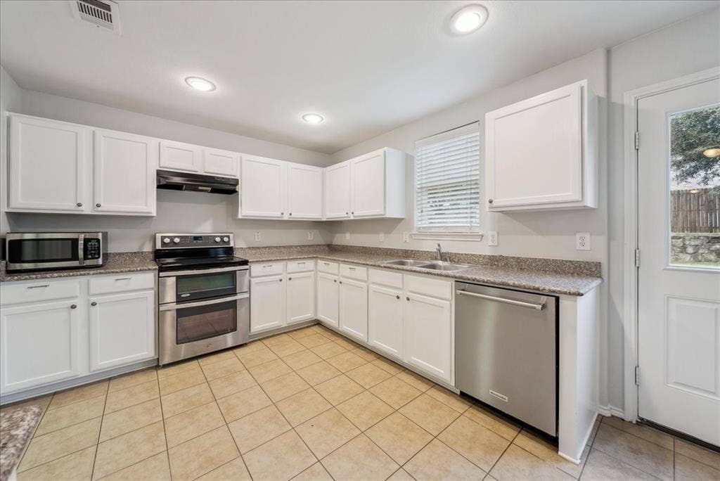 Kitchen featuring white cabinetry, light-toned tiled flooring, stainless steel appliances, and recessed lighting