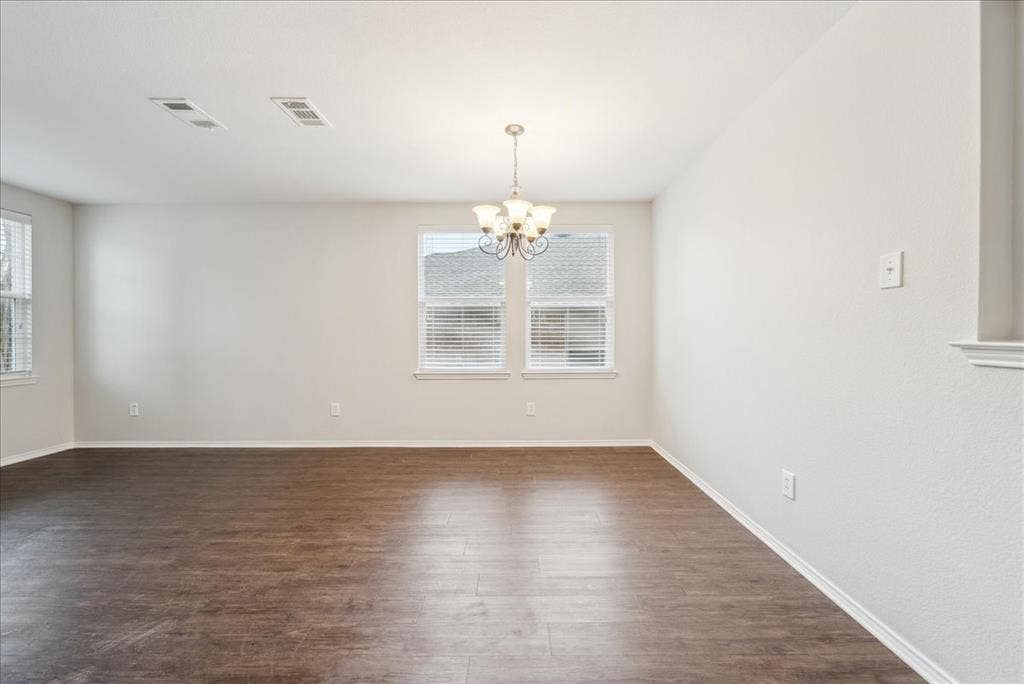 Wood-finish flooring, multiple windows with blinds, and an overhead chandelier light fixture