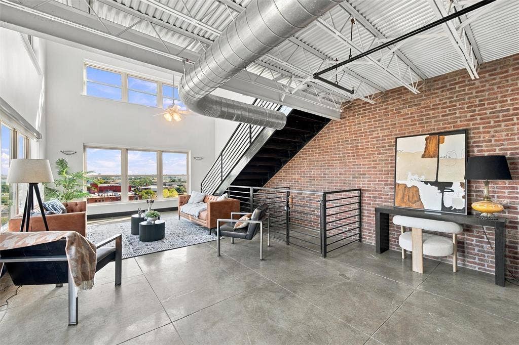 219 S 4th Street, #608, Waco, TX 76701 Exposed brick accent wall, polished concrete flooring, high ceilings, industrial-style ductwork, and a metal staircase with railing