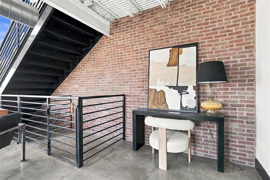 219 S 4th Street, #608, Waco, TX 76701 Exposed brick wall with industrial-style staircase featuring metal railings and concrete flooring