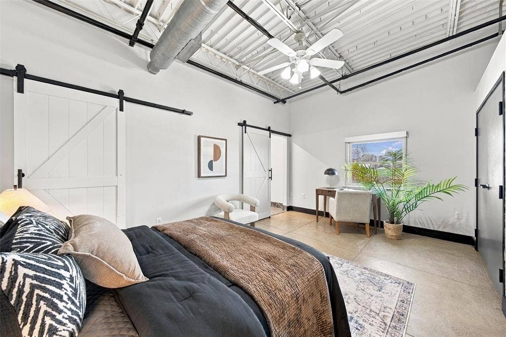 219 S 4th Street, #608, Waco, TX 76701 Vaulted ceiling with exposed ductwork, concrete flooring, dual white barn doors with black hardware, ceiling fan, and window