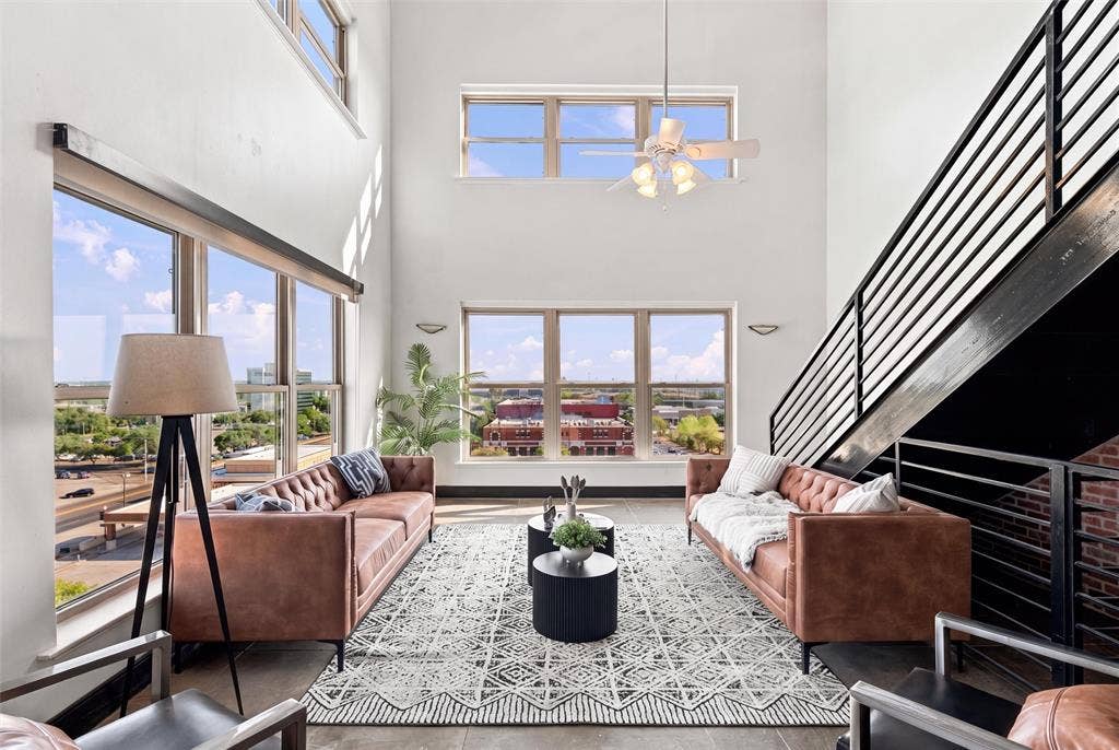219 S 4th Street, #608, Waco, TX 76701 Two-story living space featuring extensive window walls, high ceilings, a contemporary ceiling fan, and an industrial-style staircase with metal railings