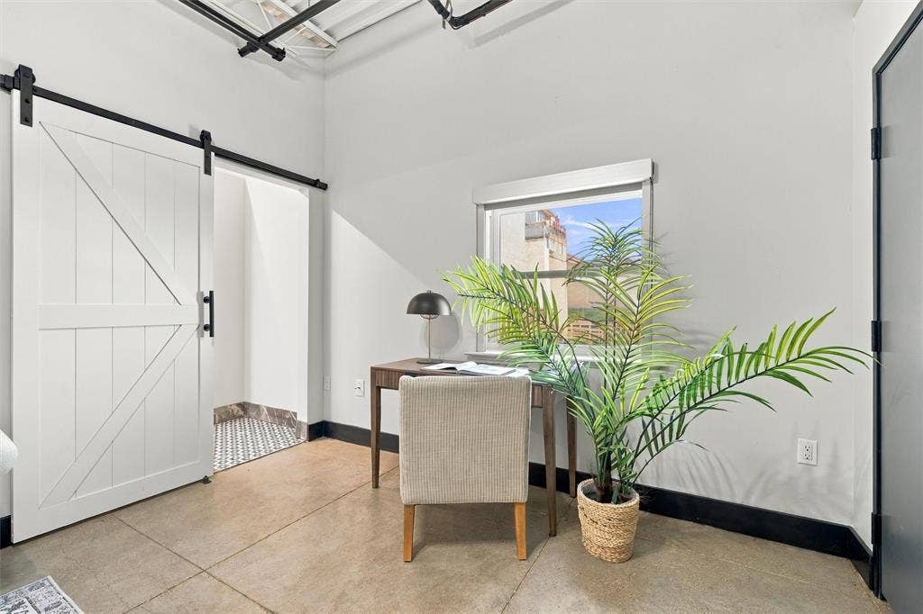 219 S 4th Street, #608, Waco, TX 76701 Concrete flooring, white barn door with black hardware, exposed ceiling, window with exterior view, and black trim