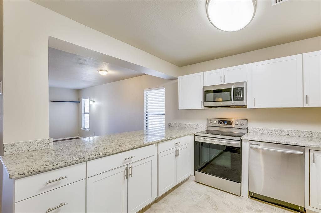 157 Harborr Drive, Gun Barrel City, TX 75156 Kitchen with stainless steel appliances, white cabinetry, light stone counters, and a peninsula