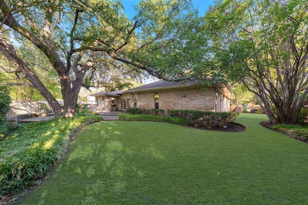 6950 Midcrest Drive, Dallas, TX 75254 Back yard grass area with mature landscaping and trees.