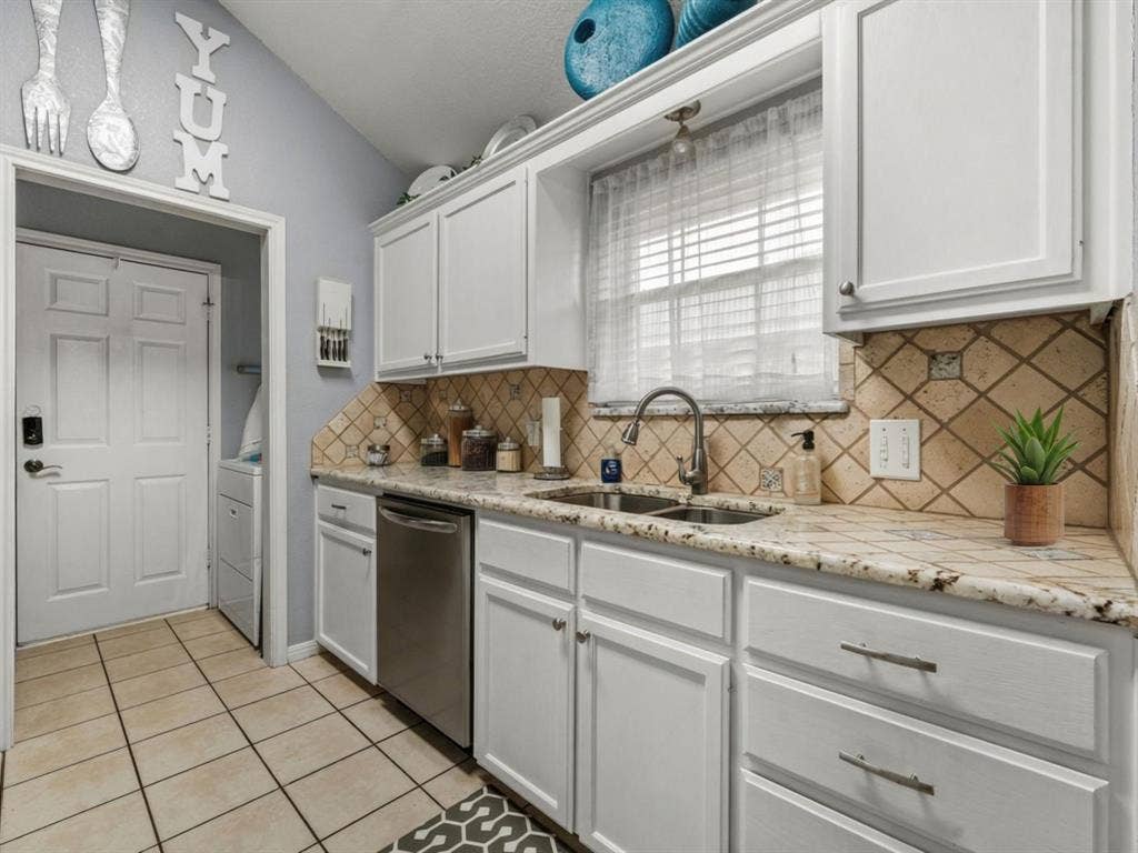 3012 Pinto Loop, Robinson, TX 76706 White cabinetry with brushed nickel hardware, light-toned tiled backsplash, granite-style countertops, stainless steel undermount double sink, and tiled flooring