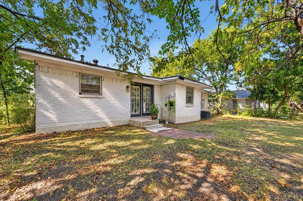 3320 Shorewood Drive, Mesquite, TX 75150 White painted brick exterior with black framed glass doors, a single window, and exterior lighting fixtures