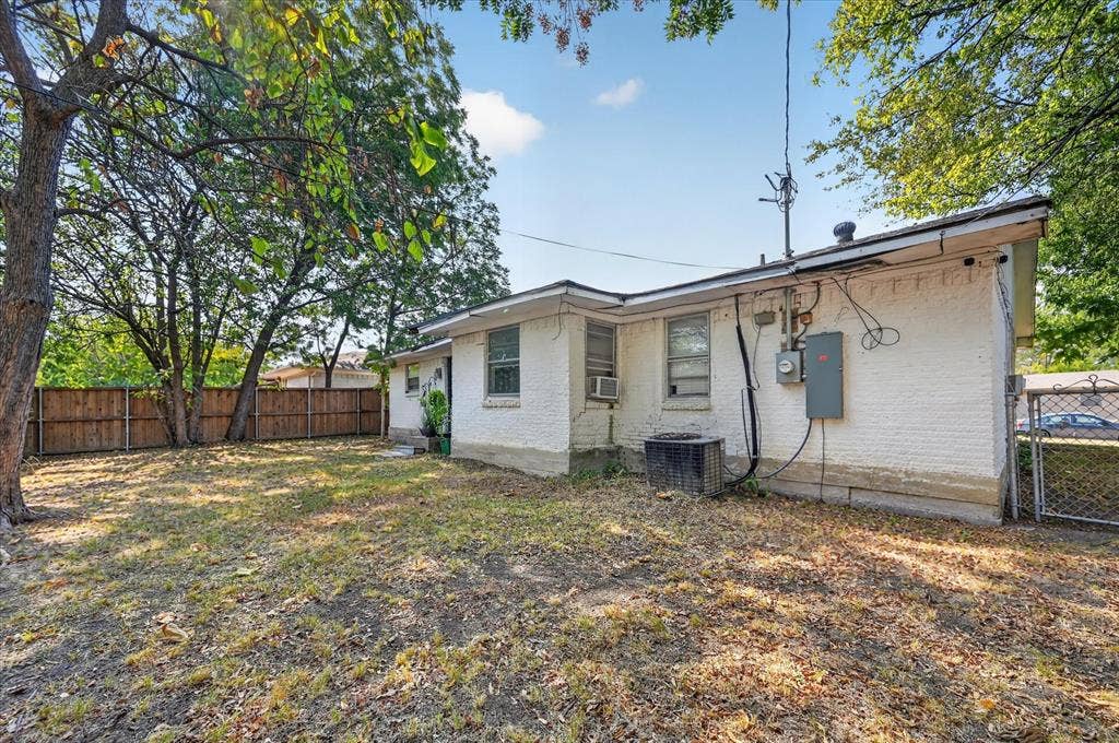 3320 Shorewood Drive, Mesquite, TX 75150 Expansive rear yard with a wood privacy fence, mature trees, and a white brick exterior