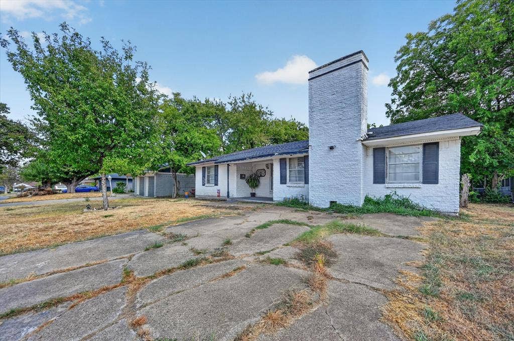 3320 Shorewood Drive, Mesquite, TX 75150 White brick exterior with dark shutters, prominent brick chimney, and mature trees