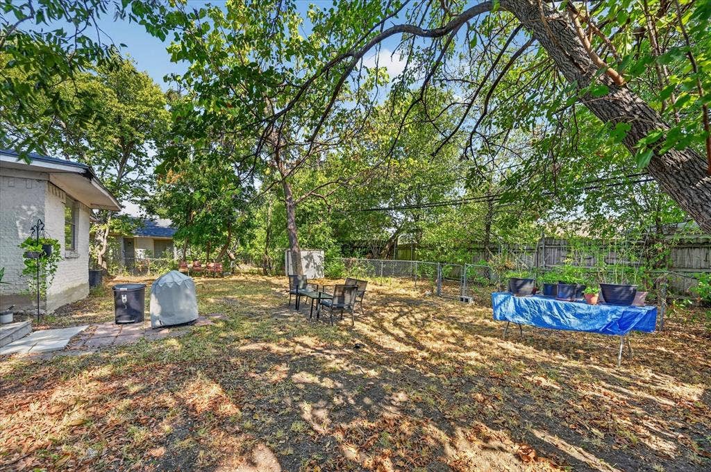 3320 Shorewood Drive, Mesquite, TX 75150 Expansive backyard featuring mature trees, a paved patio area, and a chain-link fence