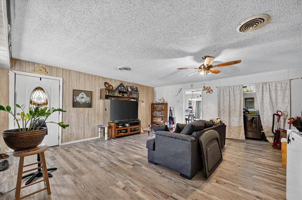 3320 Shorewood Drive, Mesquite, TX 75150 Wood-finish flooring throughout, white paneled entry door with an oval stained-glass insert, and a ceiling fan with integrated lighting