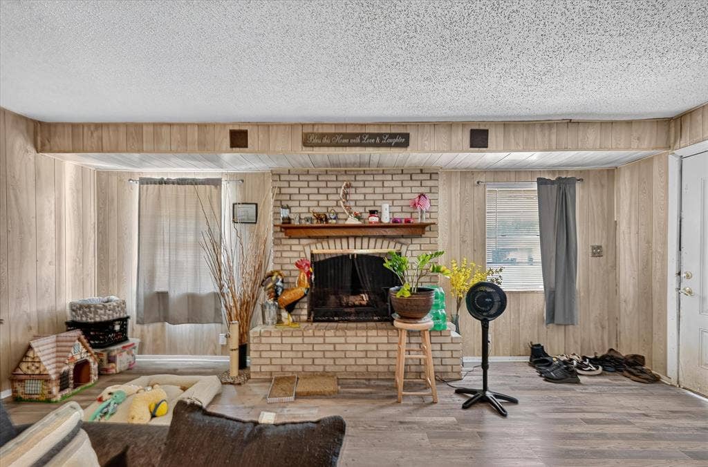 3320 Shorewood Drive, Mesquite, TX 75150 Brick fireplace with wood mantel, plank wood-finish flooring, wood paneling, and an exterior door