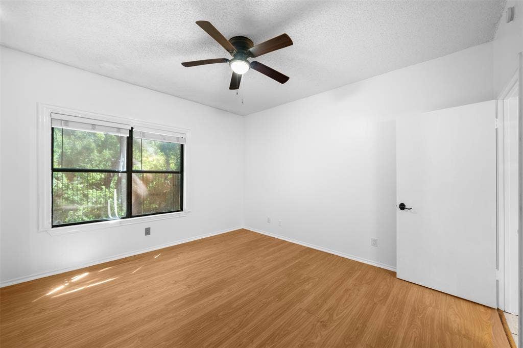 7340 Skillman Street, #909, Dallas, TX 75231 Light wood-finish flooring, a ceiling fan with integrated lighting, and a white interior door with matte black hardware
