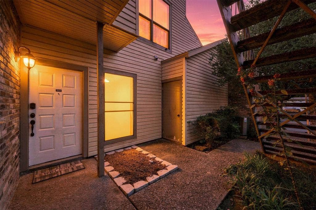 7340 Skillman Street, #909, Dallas, TX 75231 Brick and siding exterior with a paneled entry door, an exterior wall sconce, and an adjacent built-in storage unit