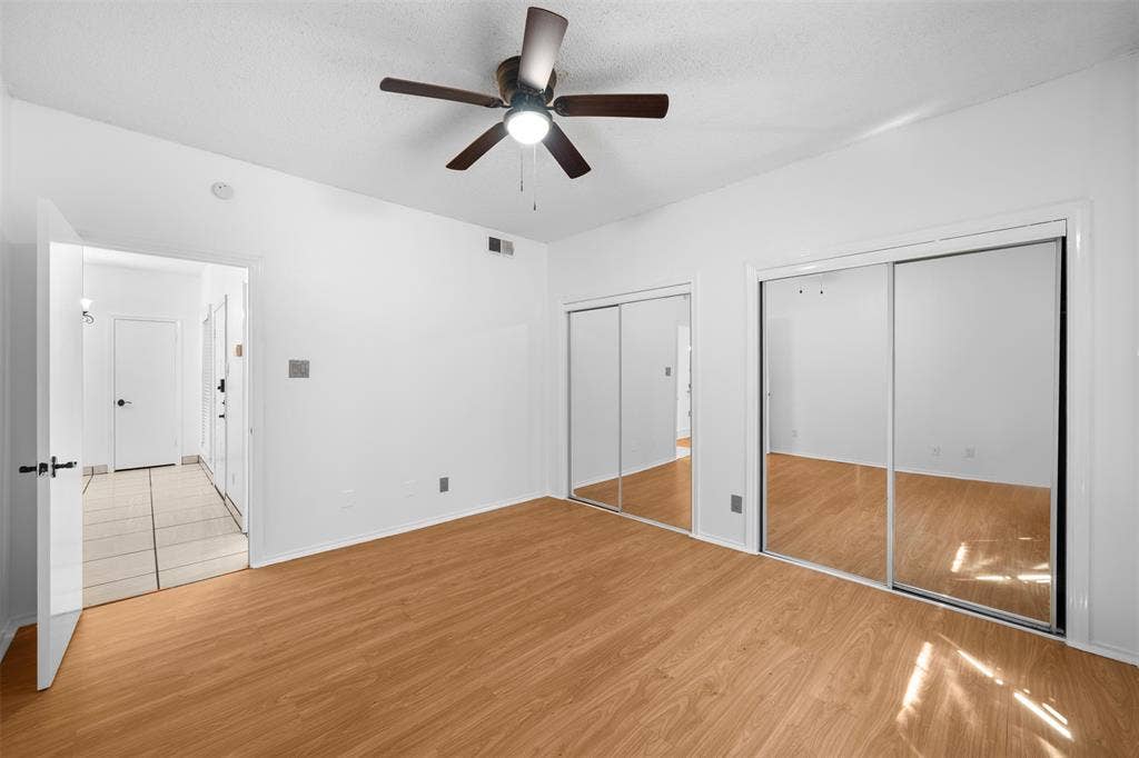 7340 Skillman Street, #909, Dallas, TX 75231 Wood-finish flooring, ceiling fan with integrated lighting, and mirrored sliding closet doors
