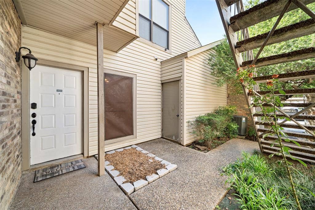 7340 Skillman Street, #909, Dallas, TX 75231 Entryway featuring a paneled door, brick exterior, and an outdoor wall sconce