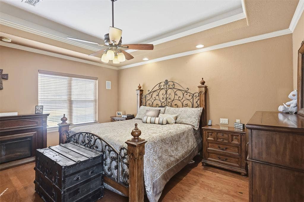 Wood-finish flooring, tray ceiling, recessed lighting, ceiling fan, and a built-in fireplace with wood mantel